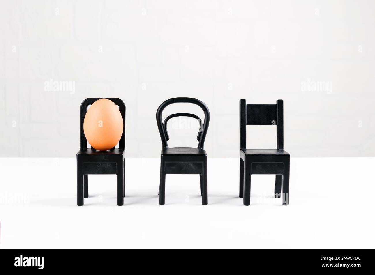 Un uovo è seduto su una sedia nera. Progettazione di idee aziendali. Concetto di individualità, esclusività. Idea di concetto di pasqua minimale Foto Stock