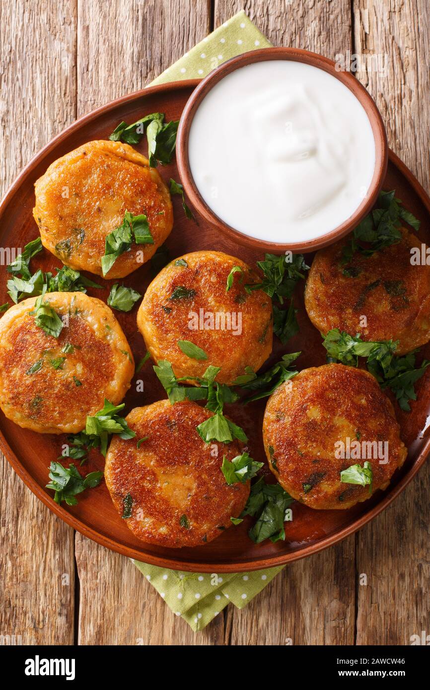 Aloo tikki è uno snack popolare dell'India del nord delle pattuglie speziate e croccanti della patata con lo yogurt primo piano in un piatto sul tavolo. Vista dall'alto verticale Foto Stock