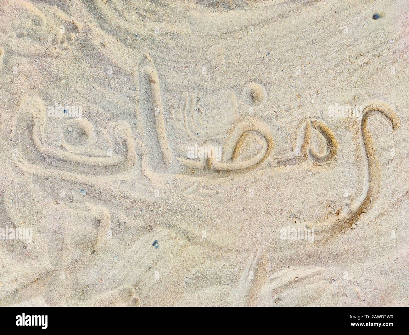 Ramadan parola in arabo, scrittura a mano sulla sabbia dorata calda, scritta. Sfondo del biglietto di auguri Foto Stock