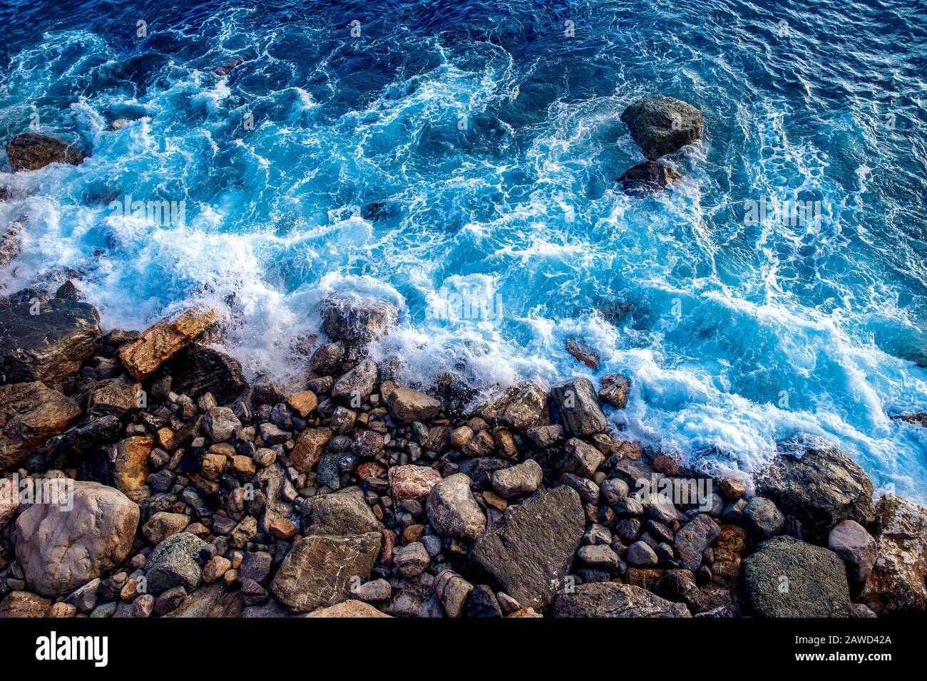 Primo piano del drone aereo. Forti onde di mare blu lavare spiaggia rocciosa selvaggia con grandi pietre Foto Stock