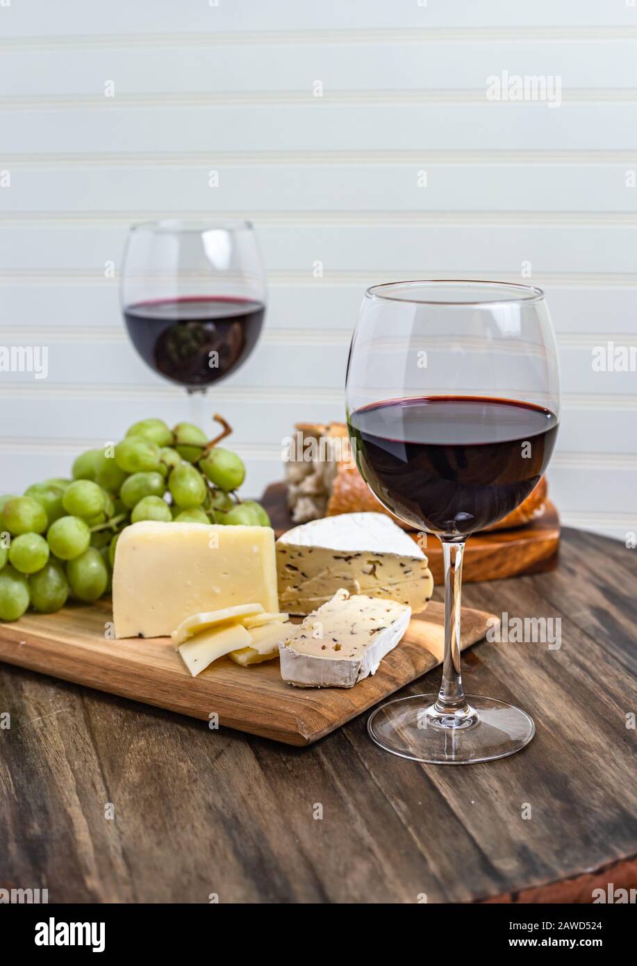 Piatto di vino e formaggio servito con uve su superficie di legno con sfondo bianco Foto Stock