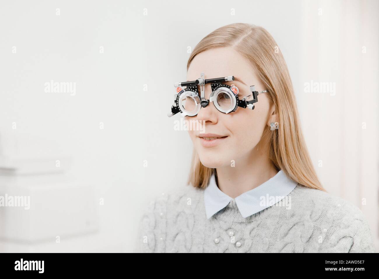 Ritratto tre quarti di bella ragazza dai capelli giusti con bocca socchiusa speciali occhiali oftalmici per controllare la visione e la selezione di lenti in professio Foto Stock
