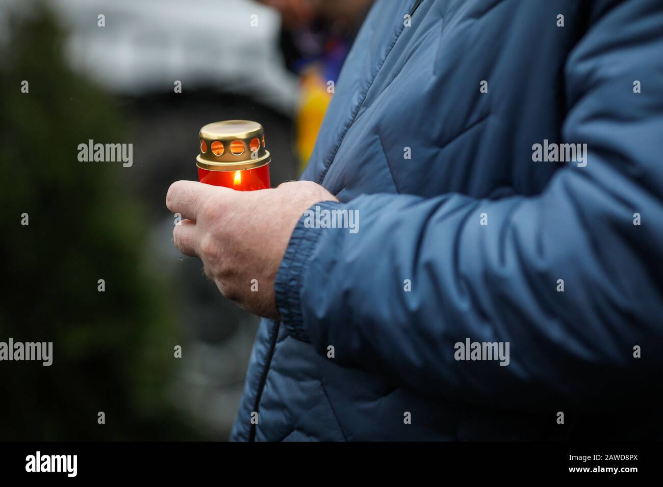 Profondità di campo poco profonda (fuoco selettivo) immagine con le mani di un uomo che tiene una candela all'aperto in una giornata fredda piovosa. Foto Stock