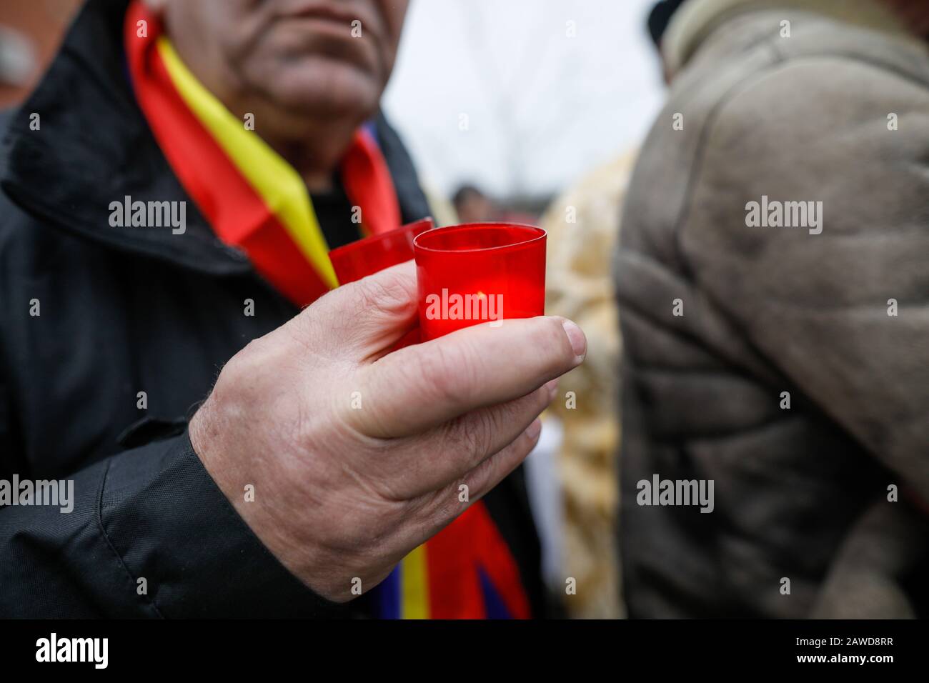 Profondità di campo poco profonda (fuoco selettivo) immagine con le mani di un uomo che tiene una candela all'aperto in una giornata fredda piovosa. Foto Stock