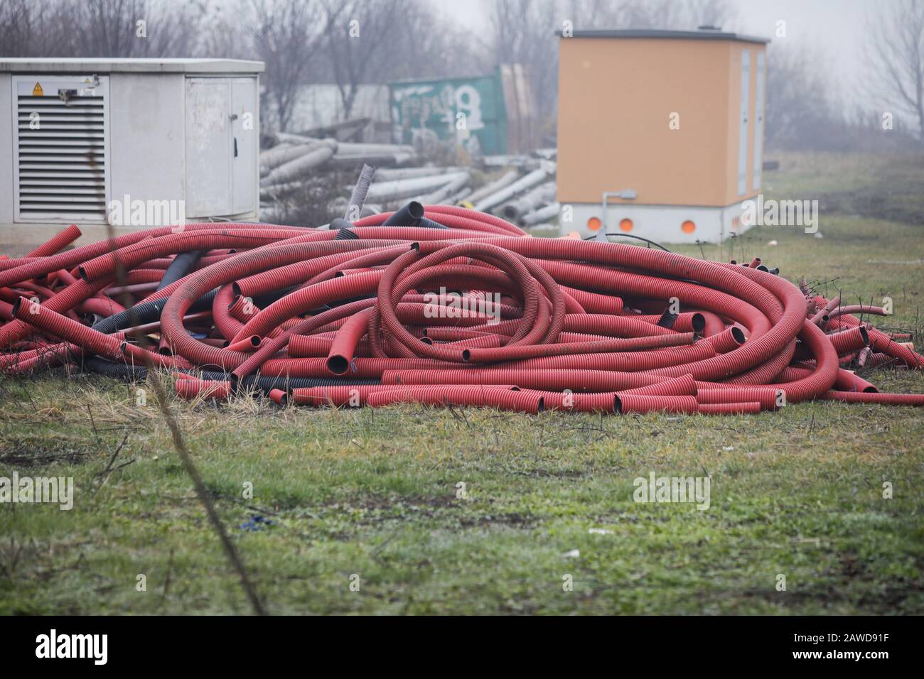 Resti di grandi protezioni esterne in plastica per cavi elettrici interrati all'aperto in una giornata fredda piovosa. Foto Stock
