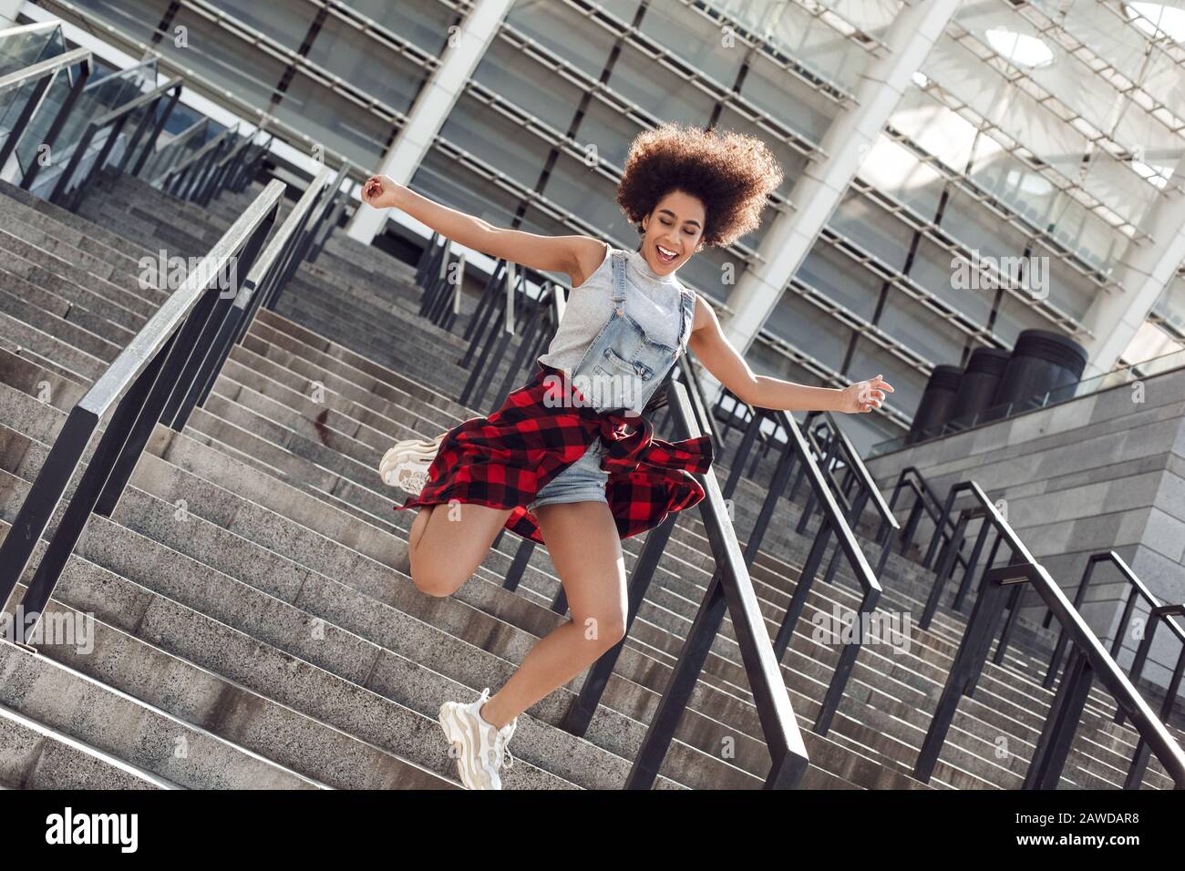 Giovane donna nella città strada saltando su scale gamba fino alla ricerca telecamera allegro Foto Stock