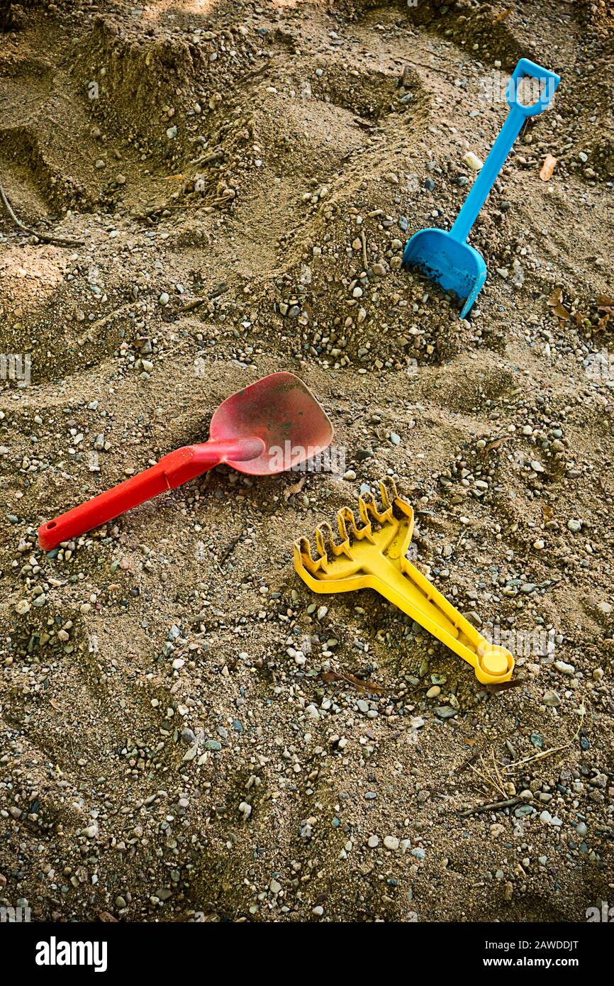 giocattoli di plastica per bambini abbandonati in un recinto di sabbia Foto Stock