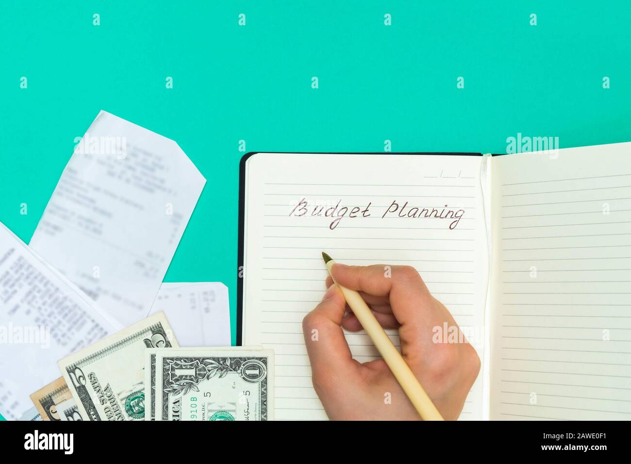 Vista dall'alto delle ricevute e dei contanti e della scrittura della mano della donna in un notepad parole pianificazione di bilancio. Concetto di budget personale Foto Stock