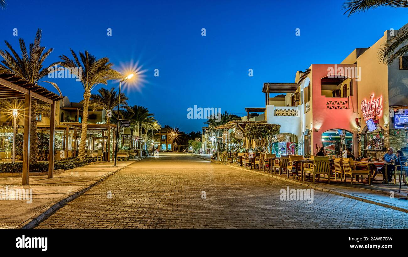 La strada principale del centro con ristoranti e alberi di palma sul marciapiede al tramonto al tramonto a el Gouna, Egitto, 16 gennaio 2020 Foto Stock