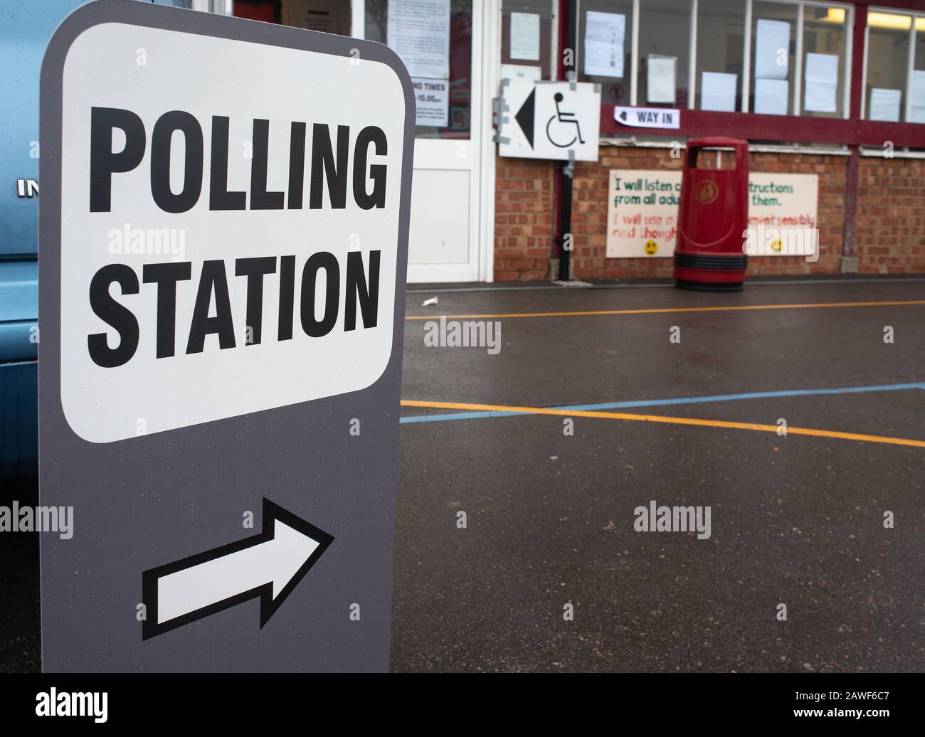 Grande stazione DI POLLING indipendente firmare in un parco giochi scuola umida, con un simbolo di freccia che punta alla zona di registrazione. Foto Stock