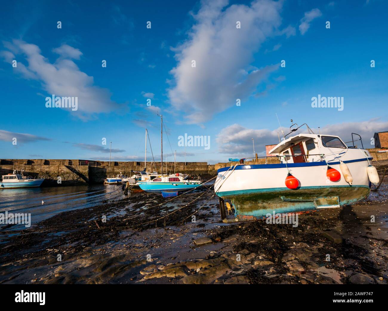 Piccole barche si agtano con la bassa marea sotto il sole, Cockenzie Harbour, East Lothian, Scozia, Regno Unito Foto Stock