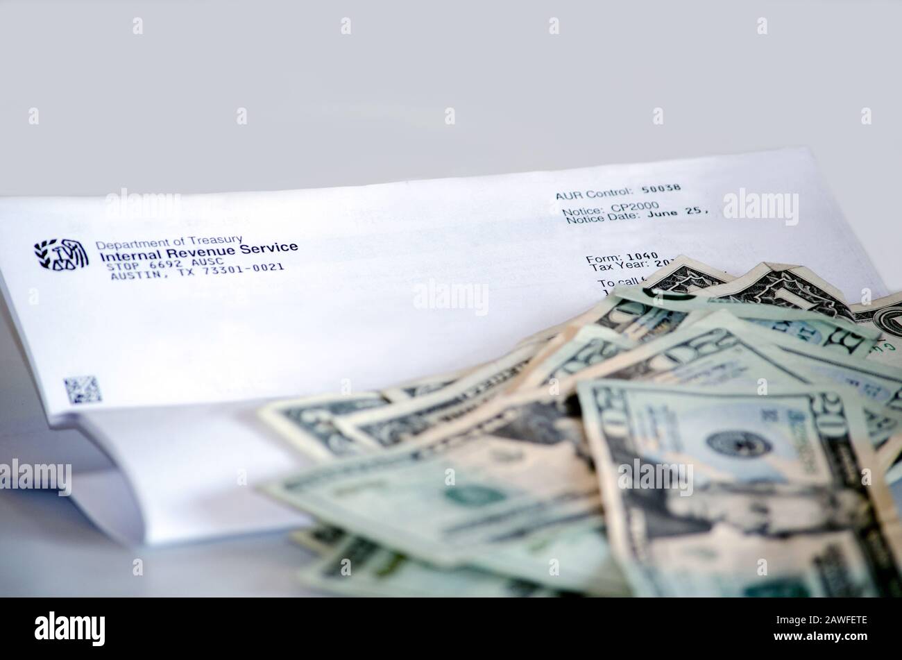Una lettera dell'IRS con una pila di valuta americana ci ricorda tutto che il tempo di imposta è qui Foto Stock