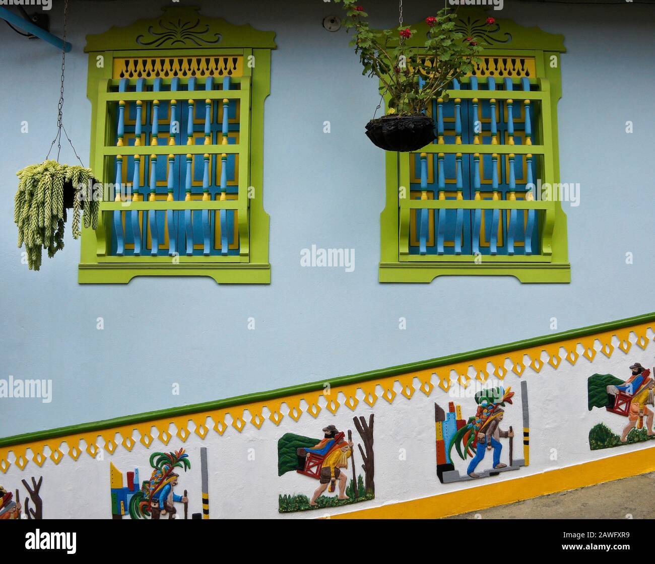 Edificio in stile coloniale decorato con finestre dipinte, piante sospese e uno zocalo (fregio), Guatape, Antiquia, Colombia Foto Stock