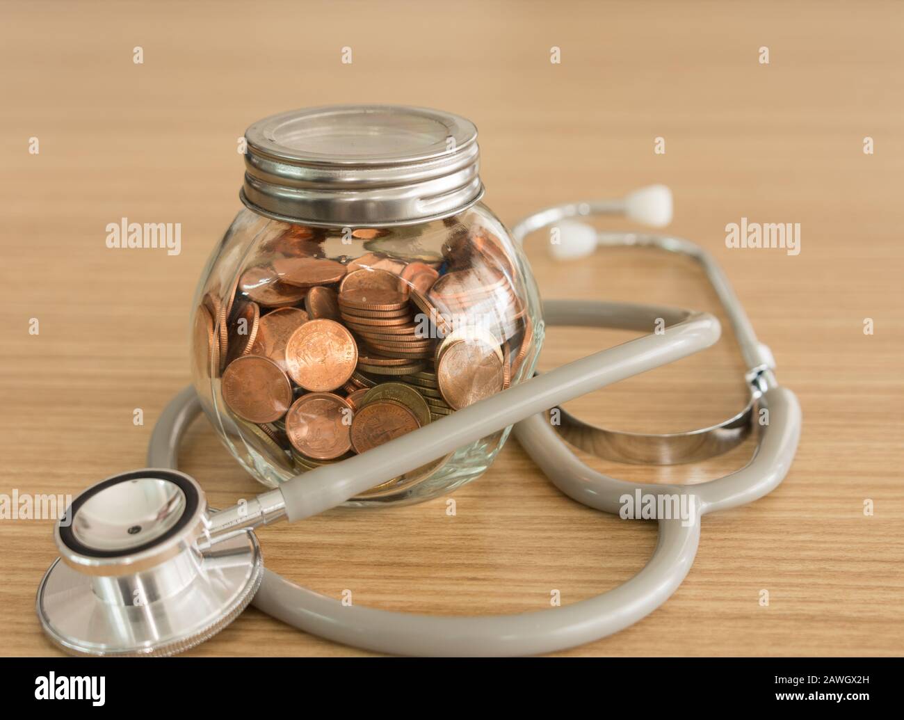 Moneta jar, stetoscopio su scrivania. Concetto di previdenza, pianificazione finanziaria personale, assicurazione sanitaria. Foto Stock