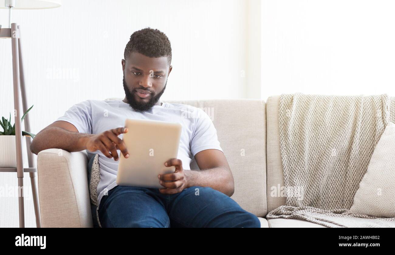 Concentrato uomo africano leggere notizie su tablet digitale Foto Stock