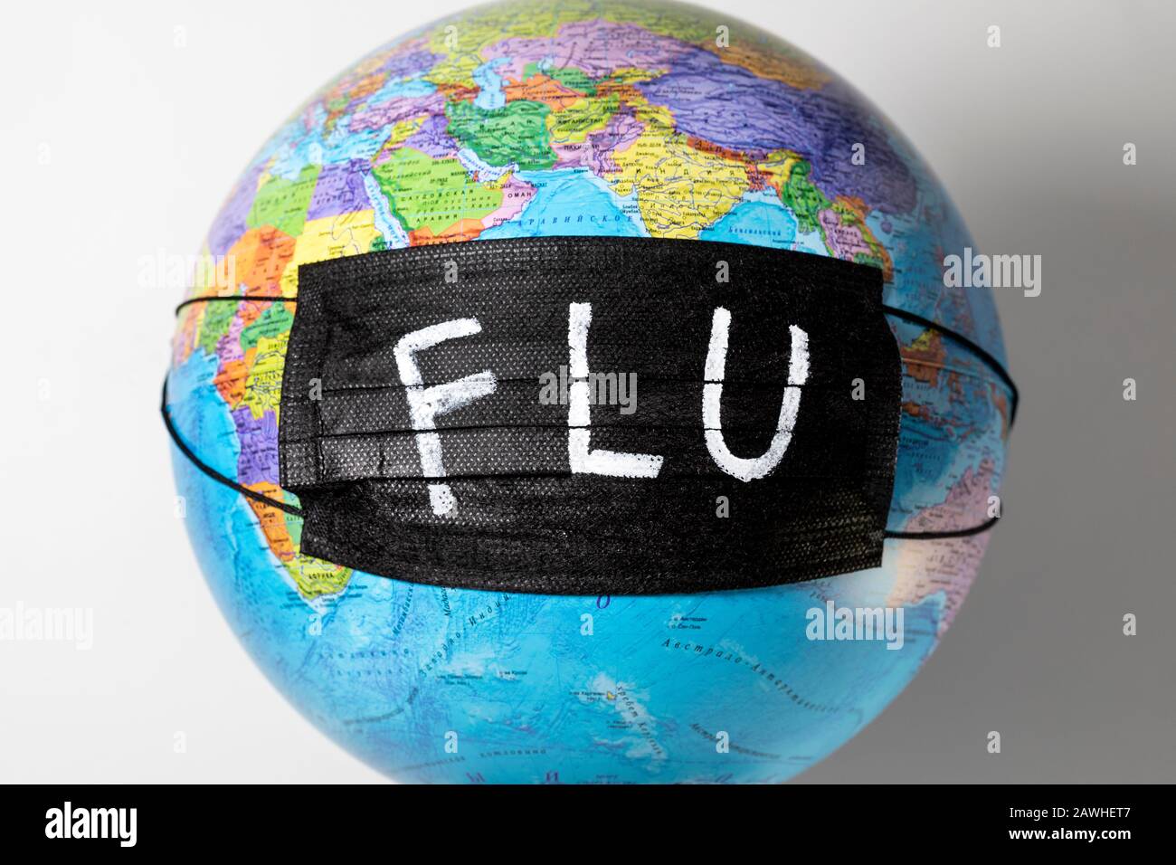 Globo con una mappa politica del mondo con una maschera medica nera e l'iscrizione `FLU` Foto Stock