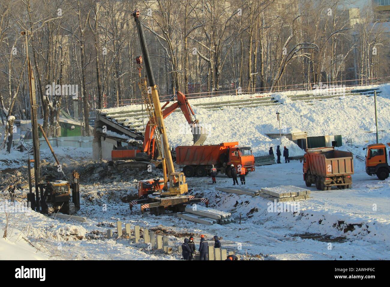 L'escavatore carica il terreno in un camion in un cantiere e la gru per camion lavora in un cantiere in inverno in Russia. Foto Stock