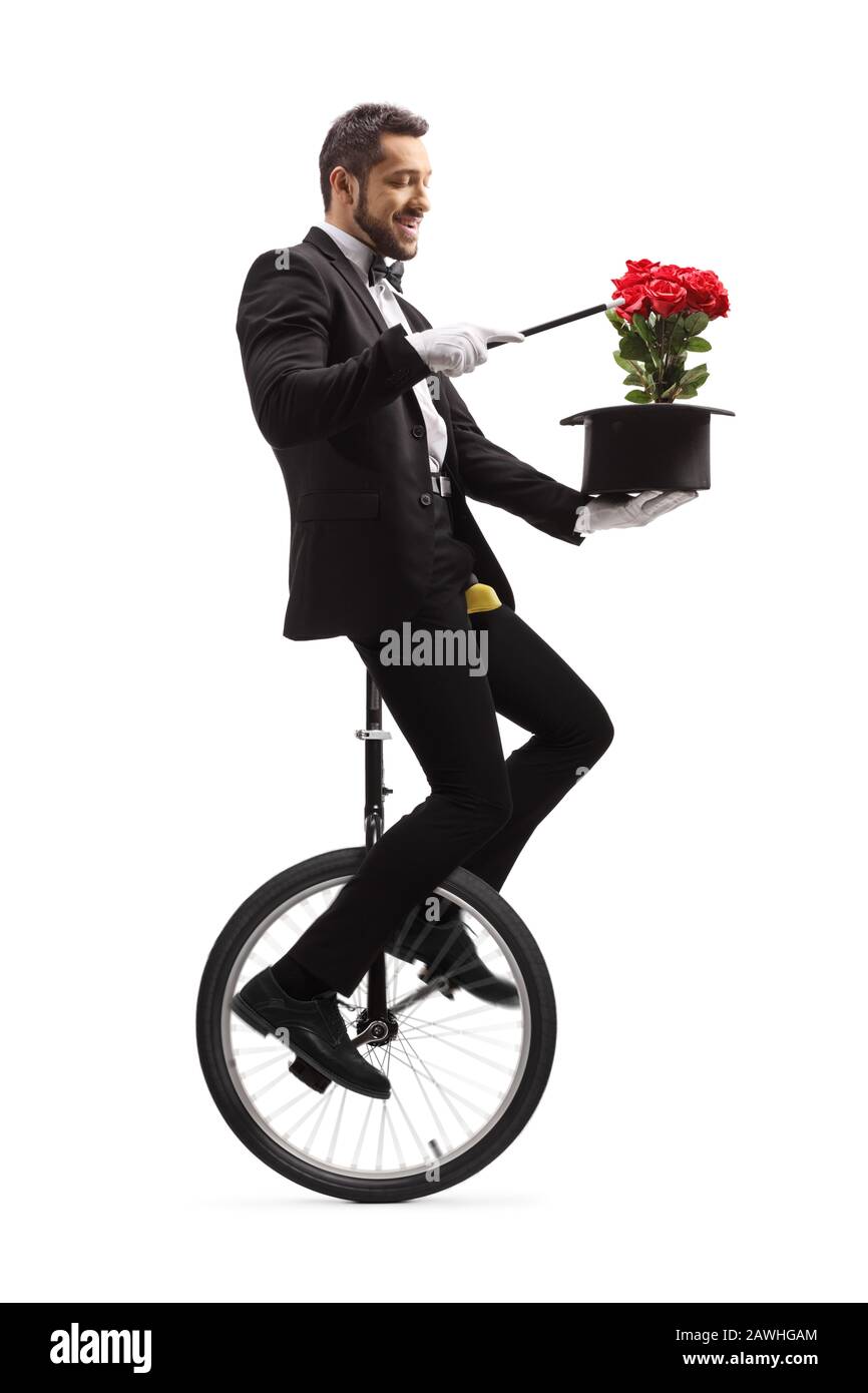 Mago che si esibisce su un monociclo con bacchetta magica, cappello e rose rosse isolate su sfondo bianco Foto Stock