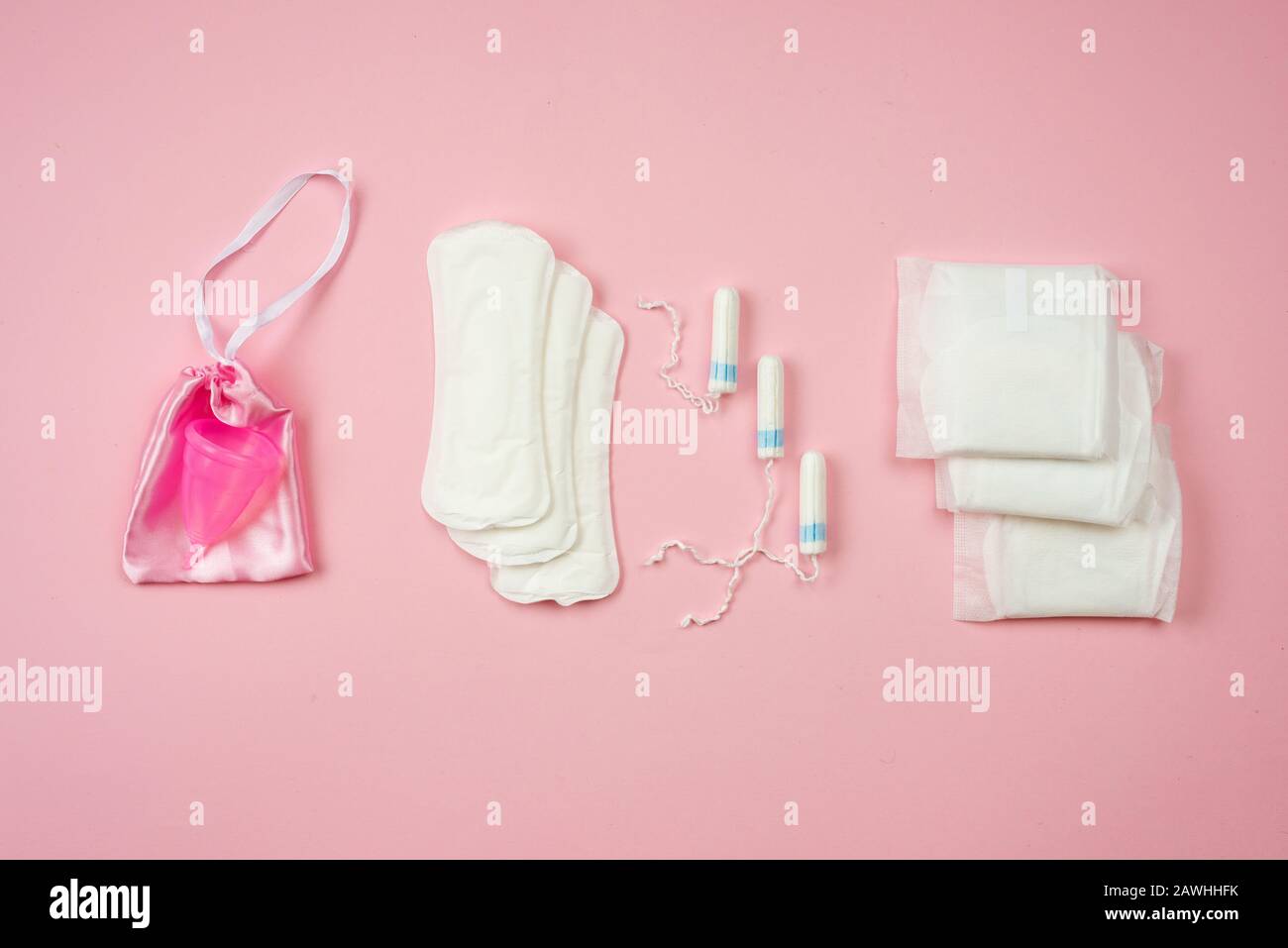 Tamponi, tamponi e coppa mestruale isolati su sfondo rosa. Concetto di protezione della donna Foto Stock