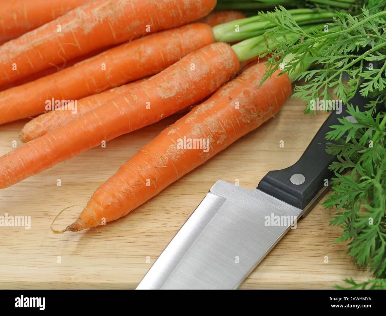 carote fresche con coltello su un tagliere di legno, primo piano Foto Stock