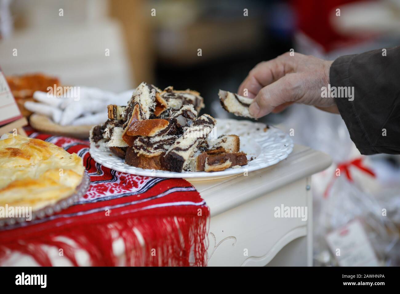 Profondità di campo poco profonda (fuoco selettivo) immagine con un uomo che prende un pezzo di coconac, dolce tradizionale rumeno durante l'inverno, da un piatto. Foto Stock