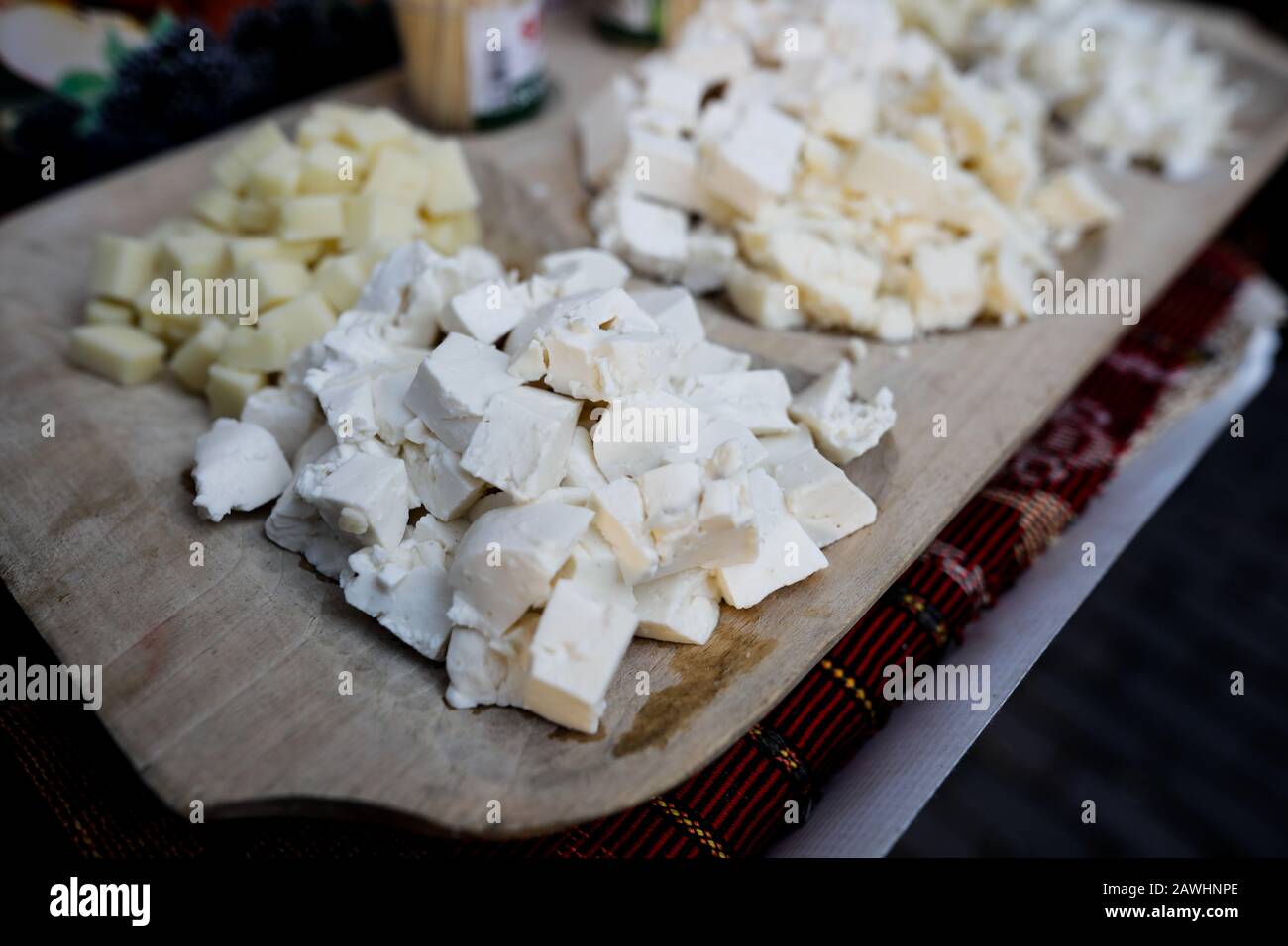 Immagine con profondità di campo bassa (fuoco selettivo) con formaggio bianco su una lastra di legno. Foto Stock
