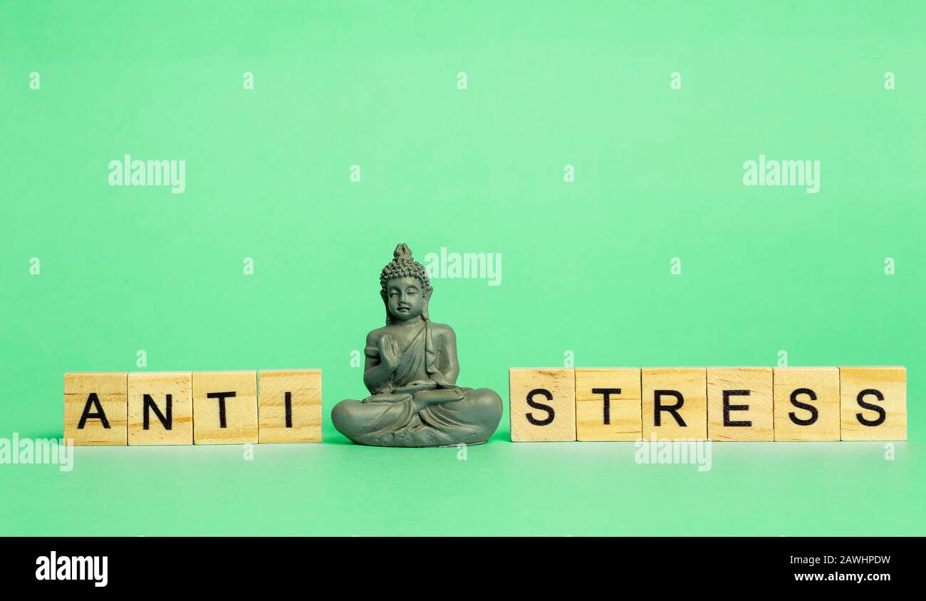 Concetto anti-stress. L'iscrizione Anti stress su sfondo verde puro con una figura meditante. Riduzione dello stress e controllo. Foto Stock