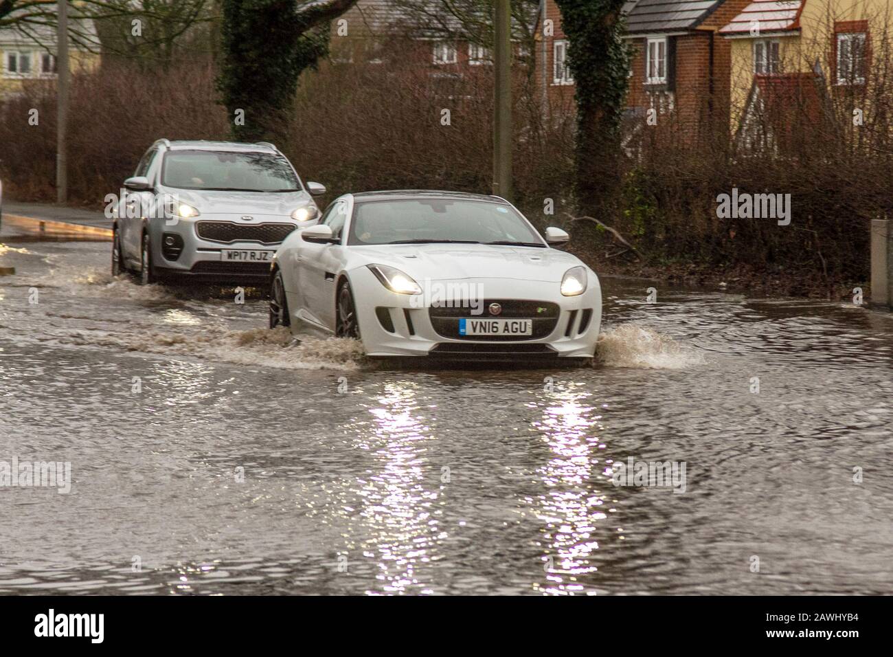 Un'auto che passa attraverso acque profonde e inondate a velocità elevata, gettando spray su una strada a Kirkham, nel Lancashire, Regno Unito. Feb, 2020. Tempo del Regno Unito; Storm Ciara strade inondato a Kirkham. Credit: MediaWorldImages/Alamy Live News Foto Stock