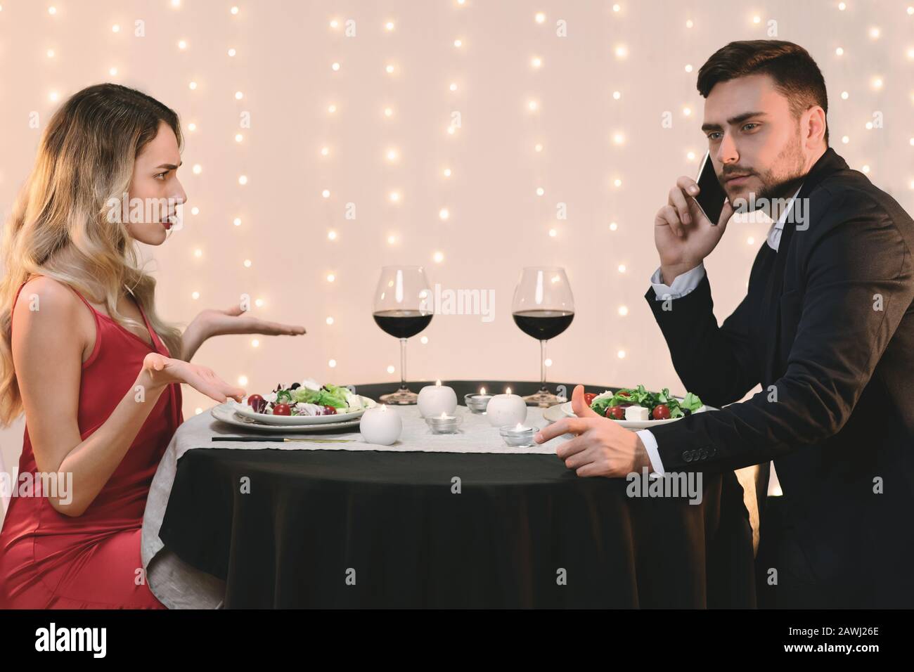 Donna Arrabbiata Incolpando Il Suo Ragazzo Che Parla Al Telefono Durante La Cena Romantica Foto Stock