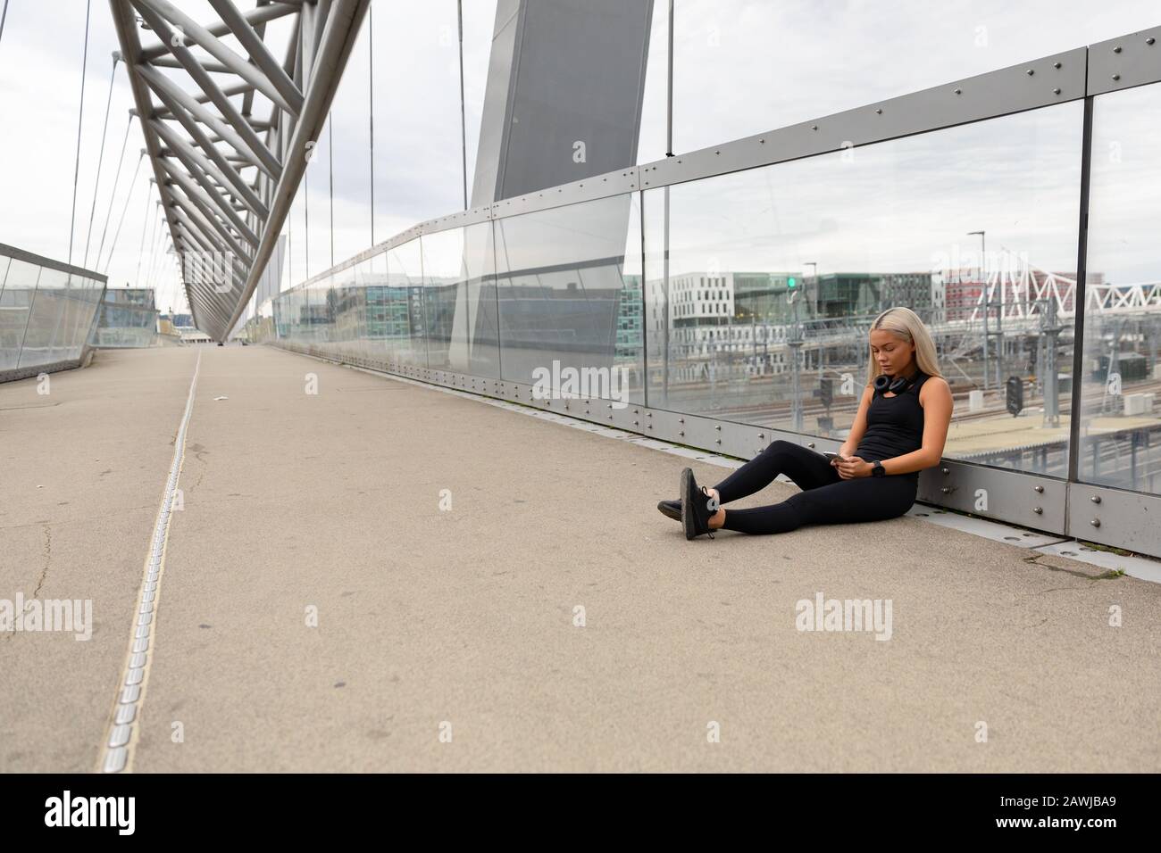 Runner Che Riposa Su Bridge Dopo L'Allenamento E Verifica Le Prestazioni Di Wokout Foto Stock