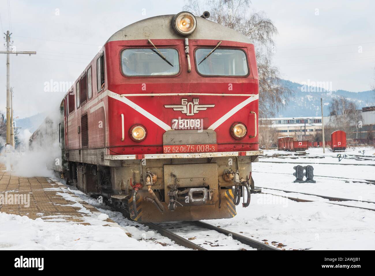 Stazione ferroviaria di Velingrad, Bulgaria - 8 febbraio 2020: Treno con locomotiva rossa e vagoni verdi arriva alla stazione ferroviaria. Foto Stock