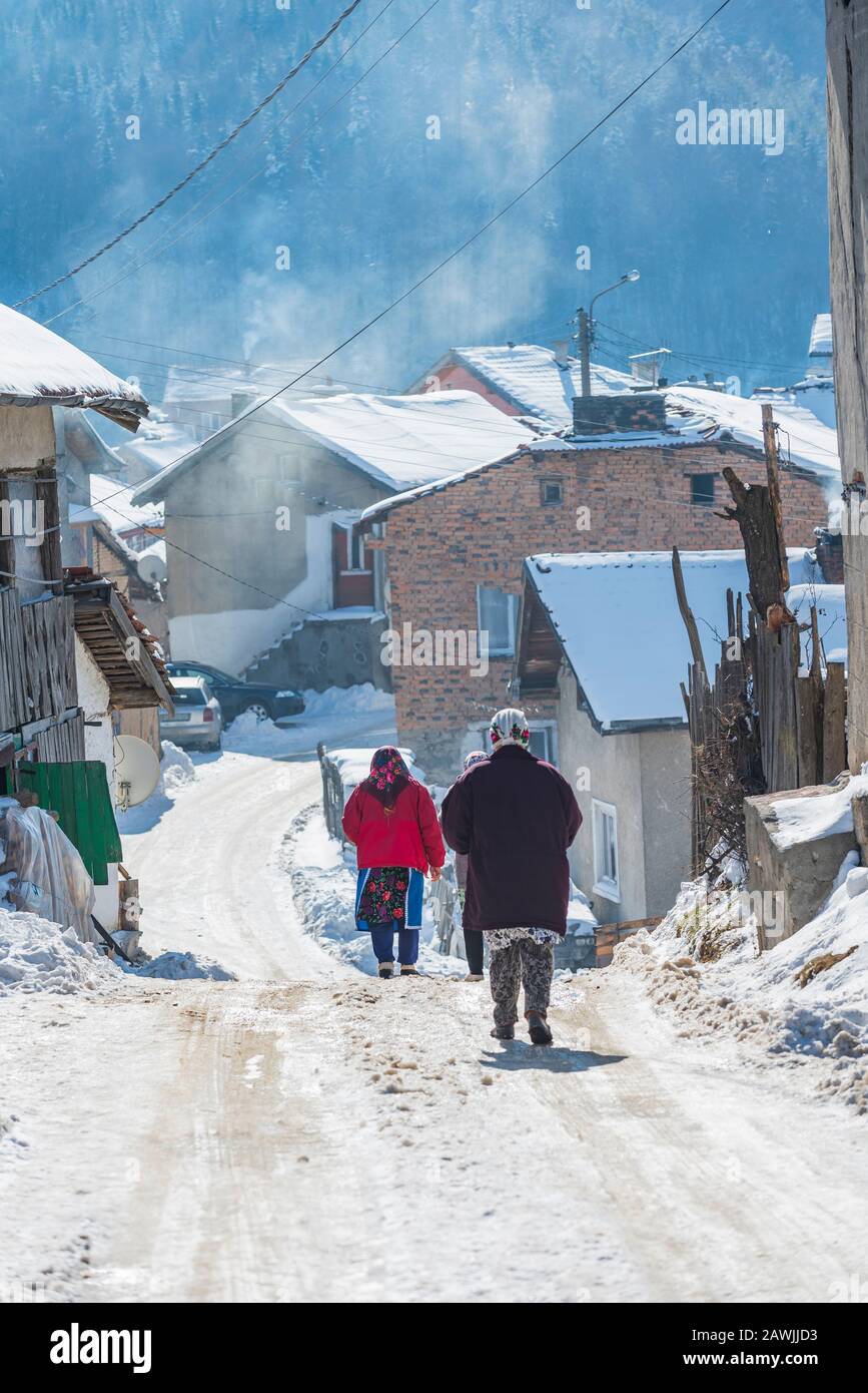 Villaggio di Grashevo, montagne di Rhodope, Bulgaria - 02.08.2020: Vecchia donna camminare su strada innevata in inverno nel villaggio di alta montagna Grashevo nel monte Rhodopi Foto Stock
