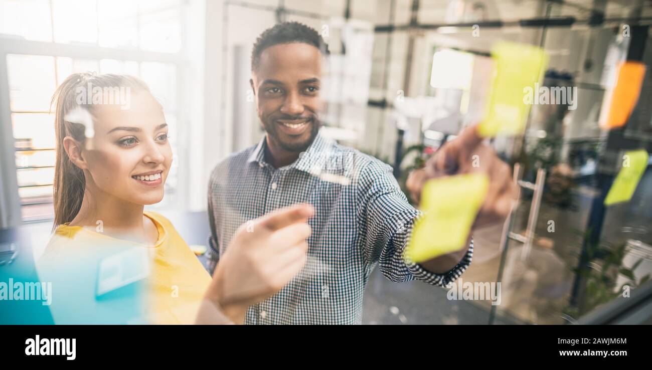 La gente di affari riunione in ufficio e uso di post-it per condividere idea. Concetto di brainstorming. Nota adesiva sulla parete di vetro. Foto Stock