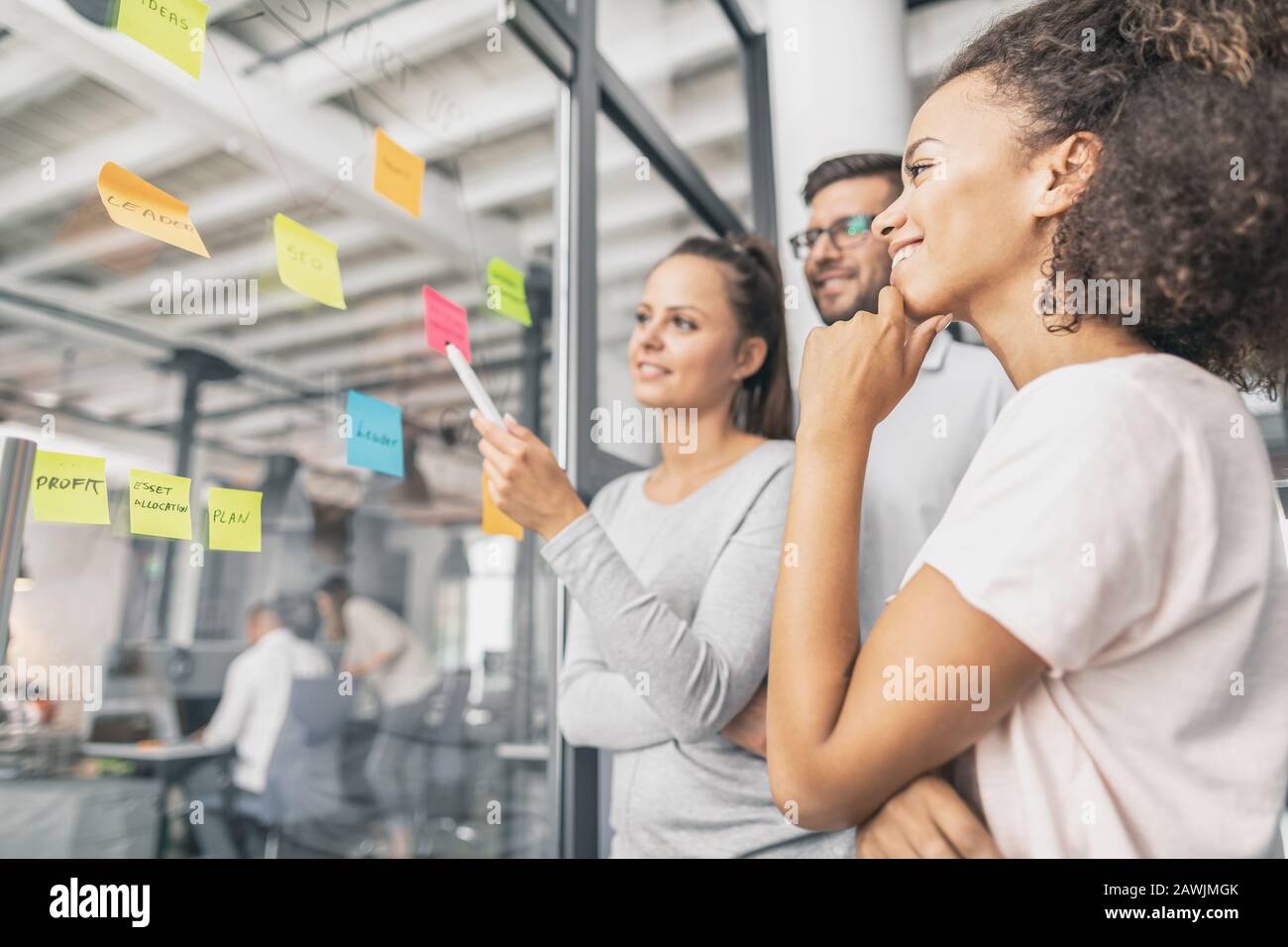 La gente di affari riunione in ufficio e uso di post-it per condividere idea. Concetto di brainstorming. Nota adesiva sulla parete di vetro. Foto Stock
