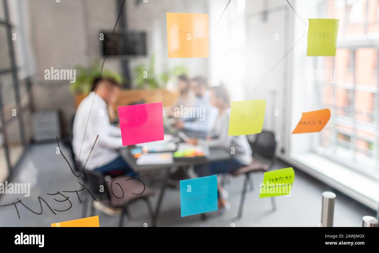 La gente di affari riunione in ufficio e uso di post-it per condividere idea. Concetto di brainstorming. Nota adesiva sulla parete di vetro. Foto Stock