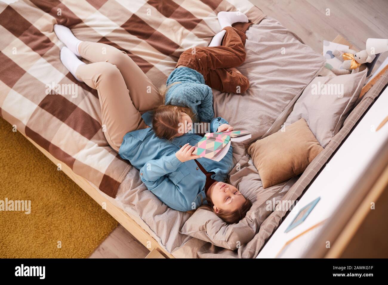 Sopra il ritratto di visione del libro di lettura della madre mentre sdraiato sul letto con la figlia dormente a casa, spazio della copia Foto Stock