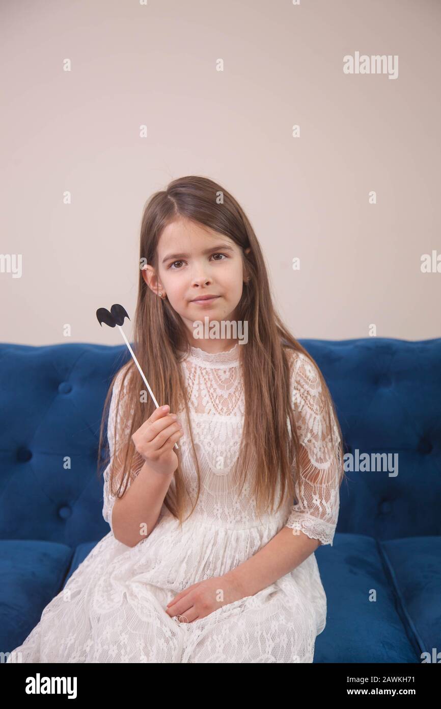 la ragazza è seduta su un divano blu in una stanza luminosa e posa Foto Stock