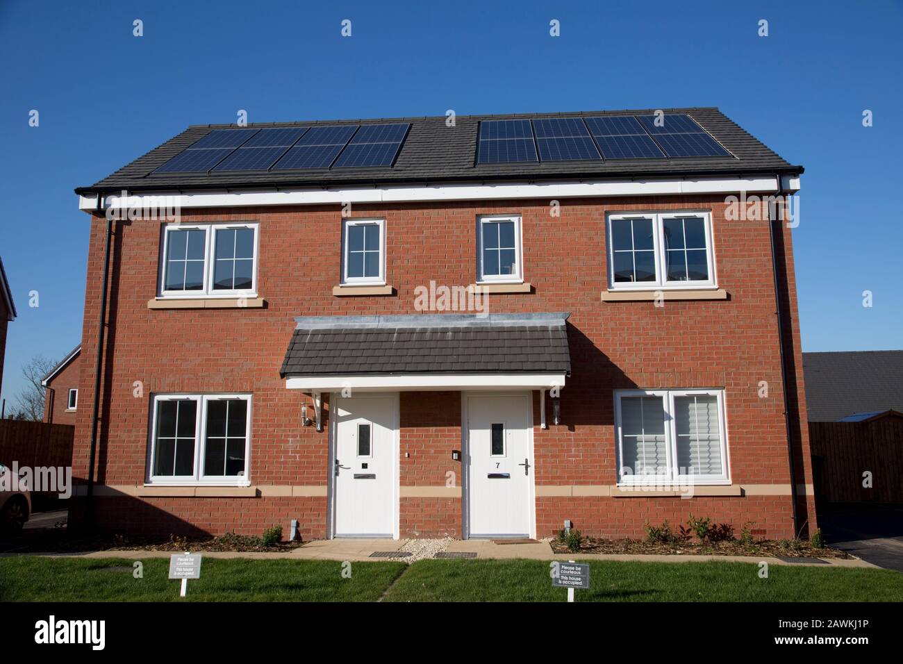 Nuove case in mattoni rossi su un piccolo sviluppo ben definito, ma solo due delle 43 case in loco hanno pannelli fotovoltaici solari. Tnese sono case apparentemente sociali Foto Stock