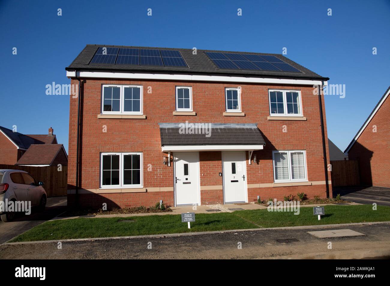 Nuove case in mattoni rossi su un piccolo sviluppo ben definito, ma solo due delle 43 case in loco hanno pannelli fotovoltaici solari. Tnese sono case apparentemente sociali Foto Stock