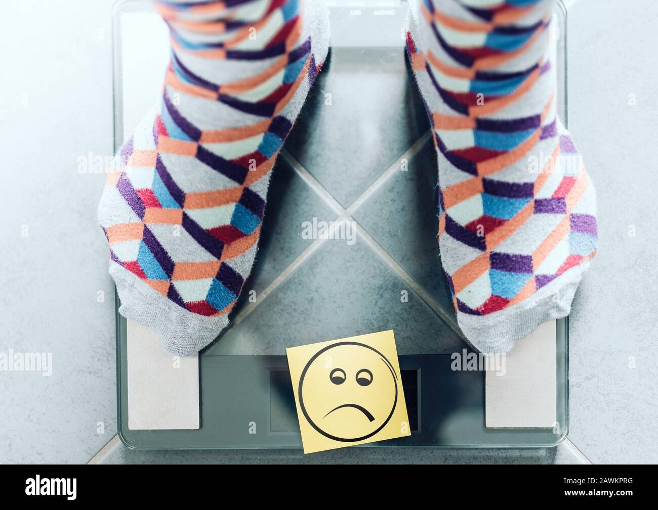 primo piano della persona in calzini su scala bagno con faccina sorridente, concetto di sovrappeso Foto Stock