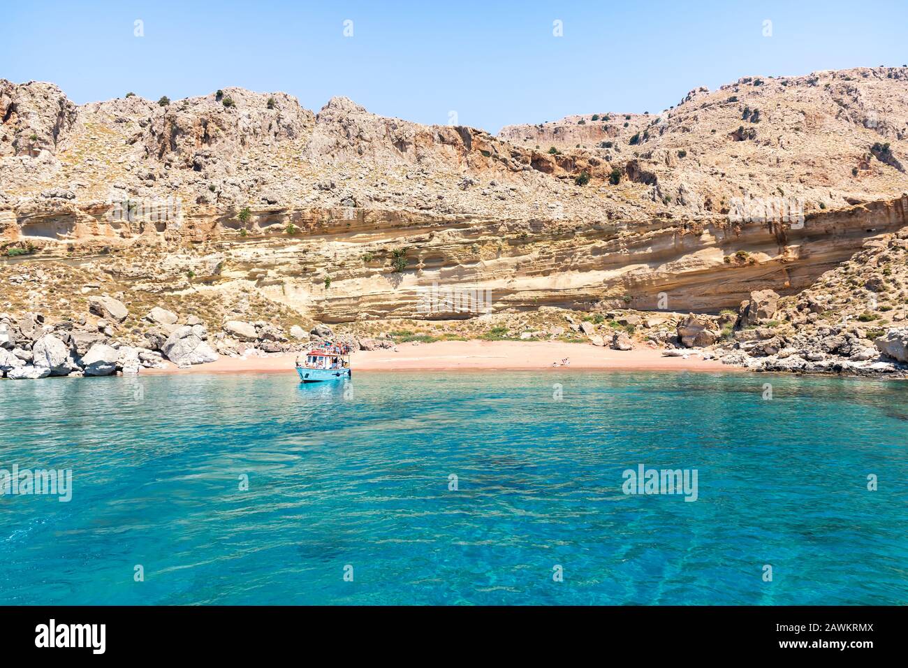 Imbarcazione turistica ancorata alla spiaggia di sabbia rossa (Rodi, Grecia) Foto Stock