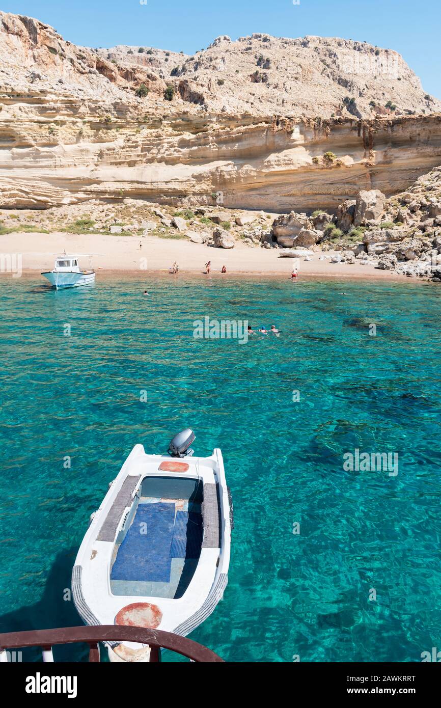 Barche turistiche ancorate dalla spiaggia di sabbia rossa, la gente ha divertimento (Rodi, Grecia) Foto Stock