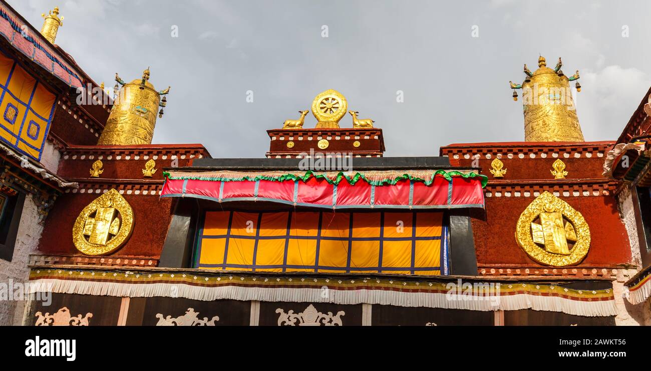 Vista sul tetto del Tempio di Jokhang. Una ruota Dharma con due cervi e due ruote di preghiera coronano il famoso tempio. Buddismo tibetano. Foto Stock