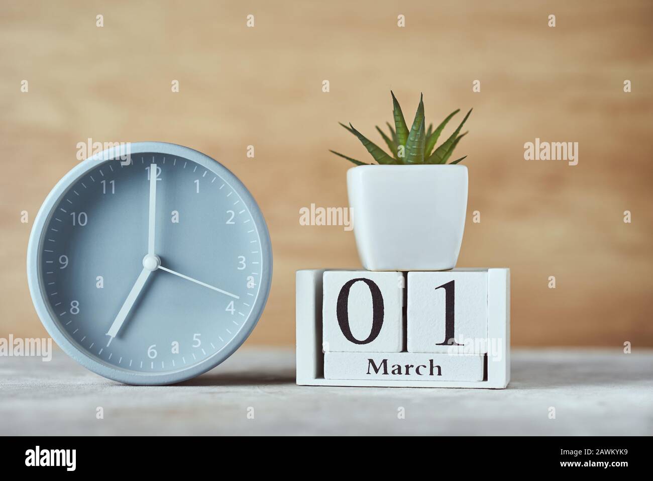 Sveglia con blocco di legno calendario data 1st marzo e pianta sul tavolo Foto Stock