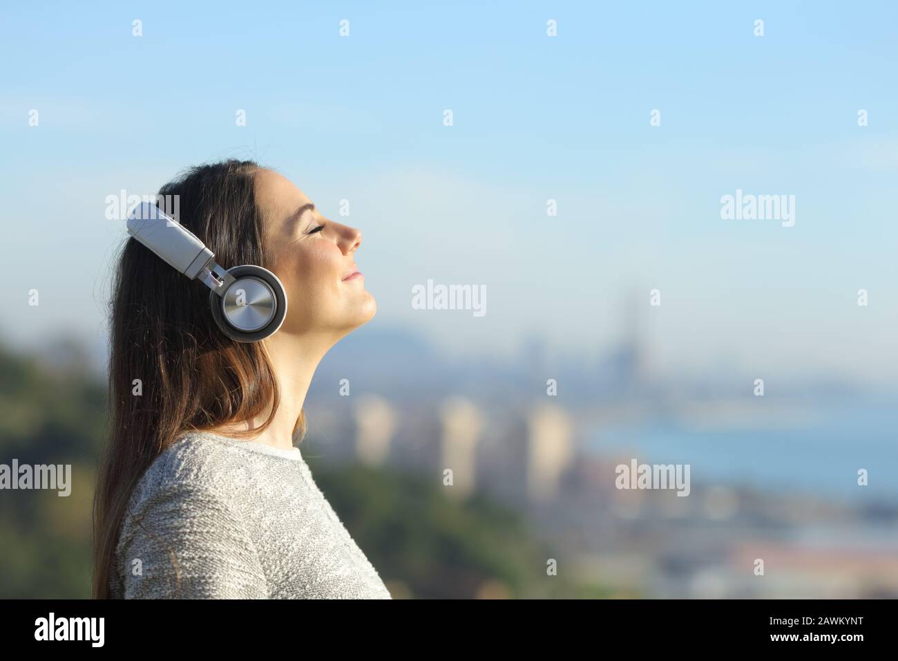 Ritratto della vista laterale di una donna che medita l'ascolto di musica indossando cuffie che respirano aria fresca all'aperto Foto Stock