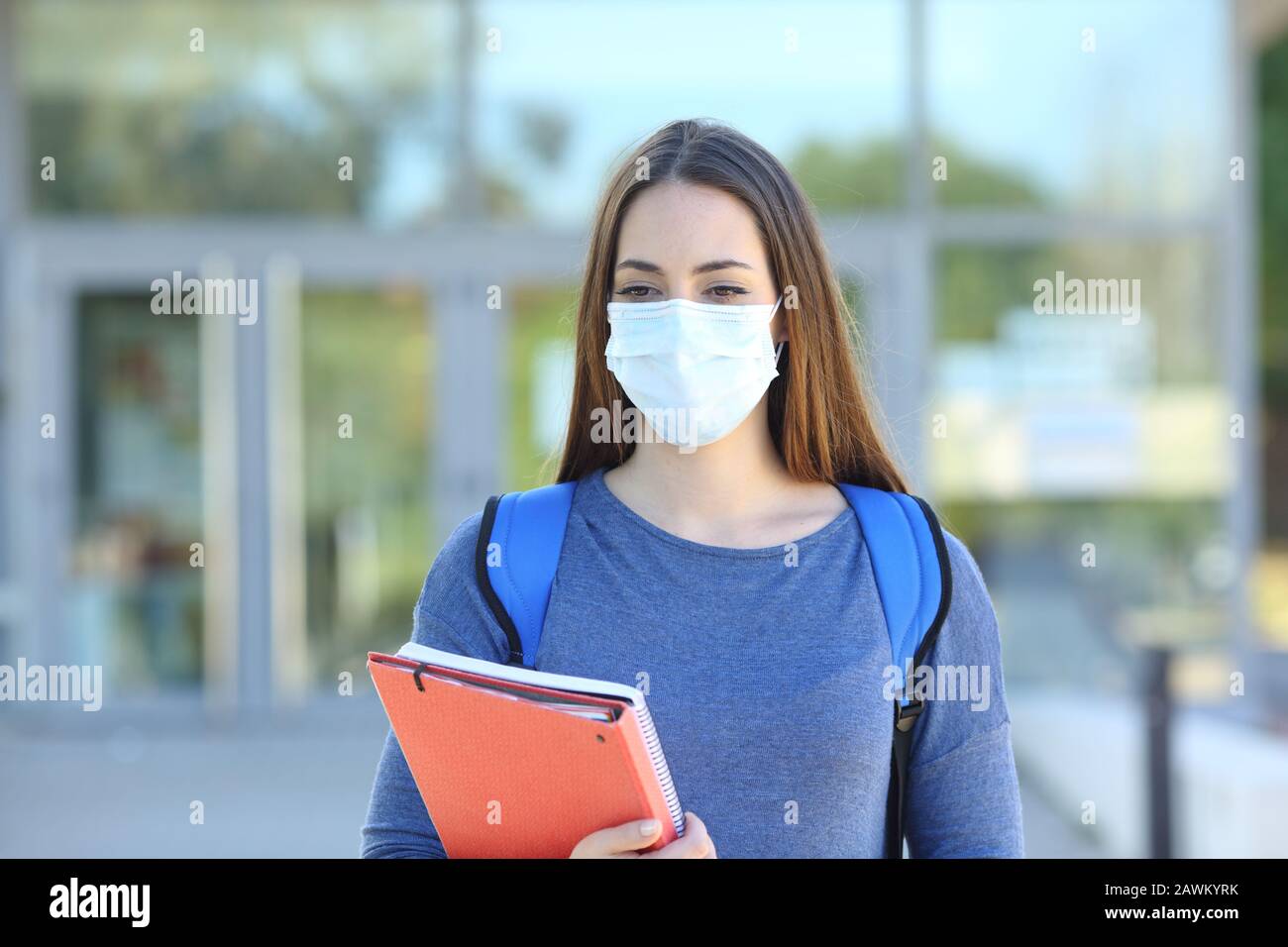 Vista frontale di uno studente che indossa una maschera protettiva che cammina in un campus Foto Stock