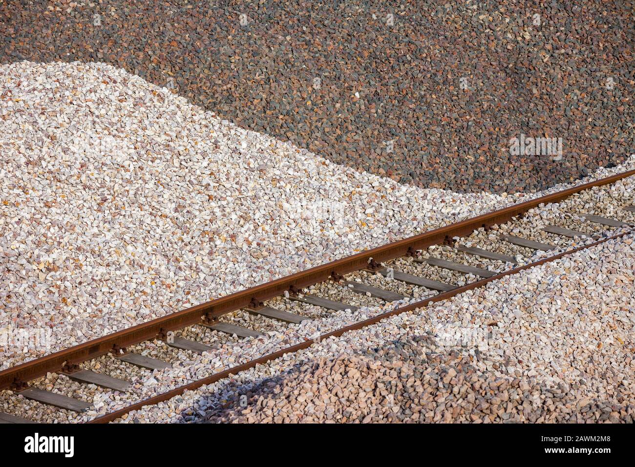 Mucchio di pietre frantumate utilizzate come zavorra nell'industria ferroviaria con binario ferroviario Foto Stock