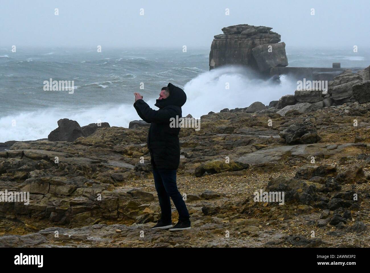 Portland Bill, Dorset, Regno Unito. 9th febbraio 2020. Meteo Regno Unito. Un uomo a Portland Bill a Dorset fotografando i mari più aspri montati dalla Storm Ciara. Foto Di Credito: Graham Hunt/Alamy Live News Foto Stock