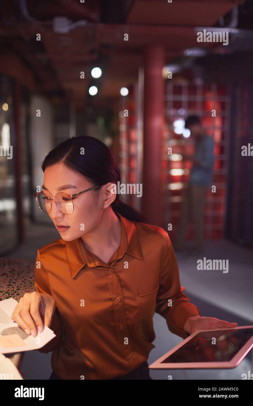 Ritratto ad alto angolo di businesswoman asiatico contemporaneo che lavora in ufficio futuristico interno, copia spazio Foto Stock