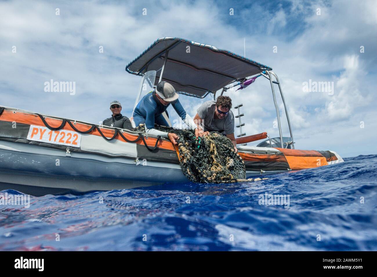 I turisti raccolgono una rete di pesca persa dal mare, Moorea, Polinesia francese Foto Stock